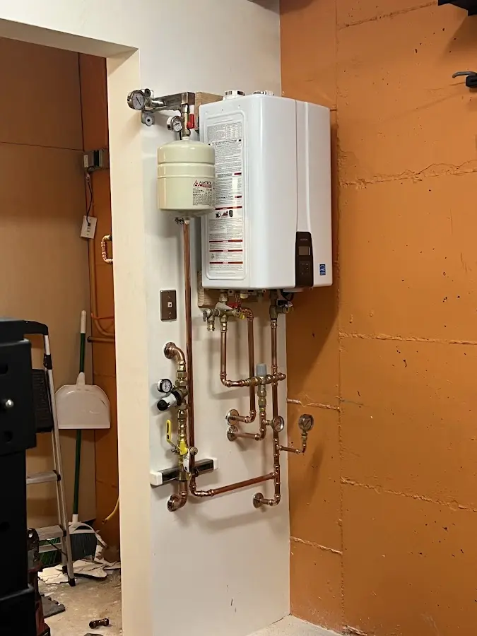 Plumbing technician inspecting water heater connections in Newbern